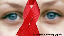 Eine Schülerin hält am Welt-AIDS-Tag eine rote Schleife in Villingen-Schwenningen in den Händen (Archivfoto vom 01.12.2003). Niemals zuvor hat sich das Aidsvirus so schnell verbreitet wie im Jahr 2004. Die etwa fünf Millionen neu infizierten Menschen treiben die Zahl der mit HIV lebenden Menschen auf weltweit fast 40 Millionen. Die höchsten Zuwachsraten verzeichnen Asien und Osteuropa, berichtet das Aisbekämpfungsprogramm UNAIDS der UN in seinem am Dienstag (23.11.2004) vorgelegten Weltaidsbericht. Foto: Patrick Seeger dpa