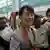 Suu Kyi makes her way through a crowd at Yangon International Airport en route to Europe