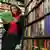 Eine Frau steht in einem Buchladen an einem Bücherregal und liest in einem Buch (Foto: picture-alliance/dpa)