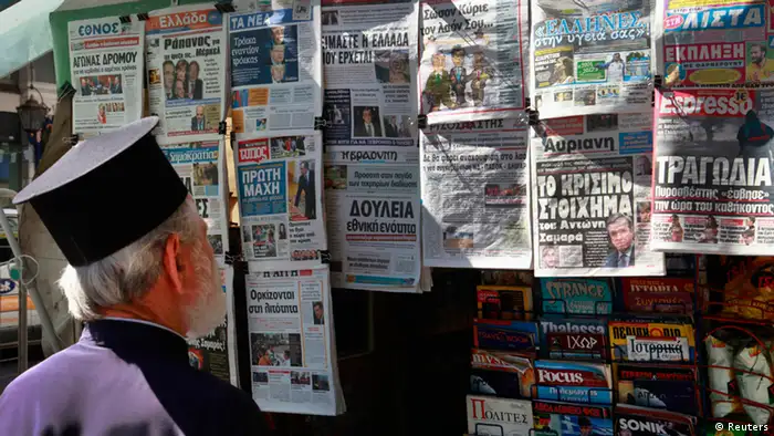 A Greek orthodox priest reads newspaper headlines on the newly elected Prime Minister June 21, 2012. Greece's new government is to ask lenders for two more years to hit fiscal targets, responding to huge public pressure for a softening of an international bailout but setting up a showdown with its euro zone partners. REUTERS/Pascal Rossignol (GREECE - Tags: RELIGION BUSINESS POLITICS)