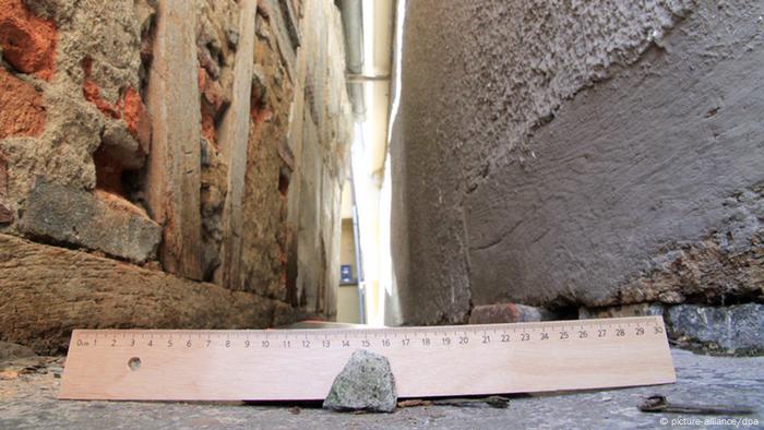 Zwischen zwei Häuserwänden liegt ein 30 cm langes Lineal.