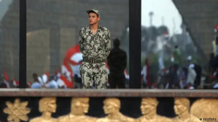 An army soldier looks on as supporters of former prime minister and current presidential candidate Ahmed Shafik shout slogans against the Muslim Brotherhood's presidential candidate Mohamed Morsy as they cheer for the Supreme Council for the Armed Forces (SCAF) in front of the military parade stand at Nasr City in Cairo June 23, 2012. Egyptians find out on Sunday whether their next president will be a former military officer or an Islamist from the army's old adversary, the Muslim Brotherhood, after a long week's wait since a vote to pick a successor to the deposed Hosni Mubarak. REUTERS/Amr Abdallah Dalsh (EGYPT - Tags: POLITICS ELECTIONS CIVIL UNREST MILITARY)