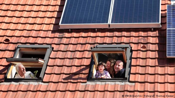 +++KfW-Bildarchiv / Fotograf: Thomas Klewar+++ Familie schaut aus Dachfenstern ihres Hauses mit Photovoltaikanlage, im April 2012, Deutschland