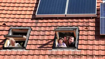 +++KfW-Bildarchiv / Fotograf: Thomas Klewar+++ Familie schaut aus Dachfenstern ihres Hauses mit Photovoltaikanlage, im April 2012, Deutschland