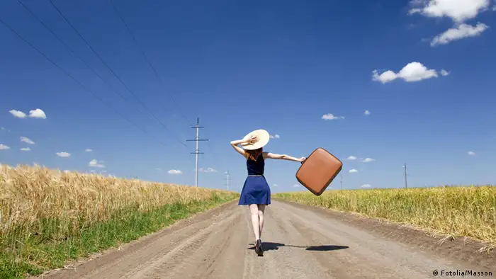 Lonely girl with suitcase at country road. Fotolia #33389308