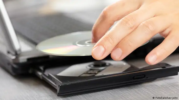 Eine Daten-CD wird in das Laufwerk eines Notebook Computers gelegt. Woman hand with CD © silver-john #25232261 - Fotolia.com