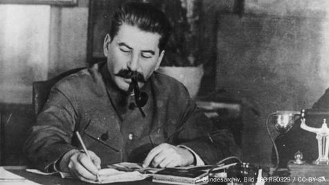 Josef Stalin, Pfeife rauchend, am Schreibtisch sitzend