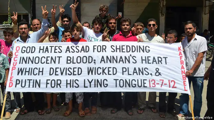 Demonstrators hold a banner as they protest against Syria's President Bashar al-Assad in Kafranbel, near Idlib July 13, 2012. REUTERS/Shaam News Network/Handout (SYRIA - Tags: POLITICS CIVIL UNREST) FOR EDITORIAL USE ONLY. NOT FOR SALE FOR MARKETING OR ADVERTISING CAMPAIGNS. THIS IMAGE HAS BEEN SUPPLIED BY A THIRD PARTY. IT IS DISTRIBUTED, EXACTLY AS RECEIVED BY REUTERS, AS A SERVICE TO CLIENTS