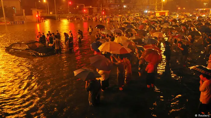 Rescuers and residents stand next to a stranded car which is being pulled up from a flooded street under the Guangqumen overpass amid heavy rainfall in Beijing, July 21, 2012. According to local media, a driver of another submerged car was confirmed dead in hospital after being pulled out critically injured at this street. The heaviest rain in 61 years that lashed Beijing Saturday have left at least four people dead and six others injured, cutting off traffic and also severely disrupted air traffic, Xinhua News Agency reported. REUTERS/Stringer (CHINA - Tags: DISASTER ENVIRONMENT TPX IMAGES OF THE DAY)