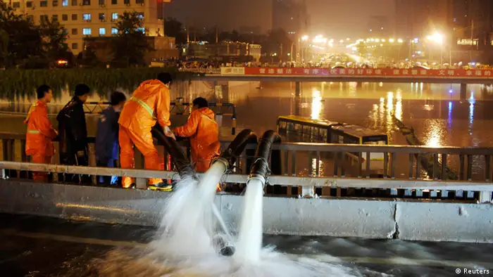 Workers pump flood water as a bus is stranded on a street amid heavy rainfalls in Beijing, July 21, 2012. The heaviest rain storm in six decades to hit the Chinese capital killed at least 10 people and caused widespread chaos, flooding streets and stranding 80,000 people at the city's main airport, state media reported on Sunday. Picture taken July 21, 2012. REUTERS/Stringer (CHINA - Tags: ENVIRONMENT DISASTER TRANSPORT) CHINA OUT. NO COMMERCIAL OR EDITORIAL SALES IN CHINA