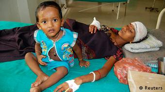 An injured local resident Prnima Das, 32, rests with her child in a hospital