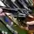 Ein Verkäufer zeigt in einem Waffengeschäft einem Kunden einen Sportrevolver der Marke Colt Python, neun Millimeter. (Foto: dpa)