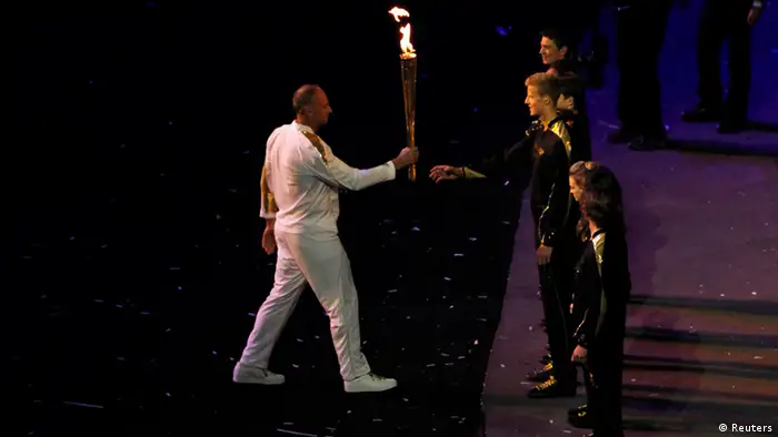 Britain's Steve Redgrave passes the Olympic Flame to one of the seven final torchbearers during the opening ceremony of the London 2012 Olympic Games in the Olympic Stadium July 27, 2012. REUTERS/Adrees Latif (BRITAIN - Tags: SPORT OLYMPICS)