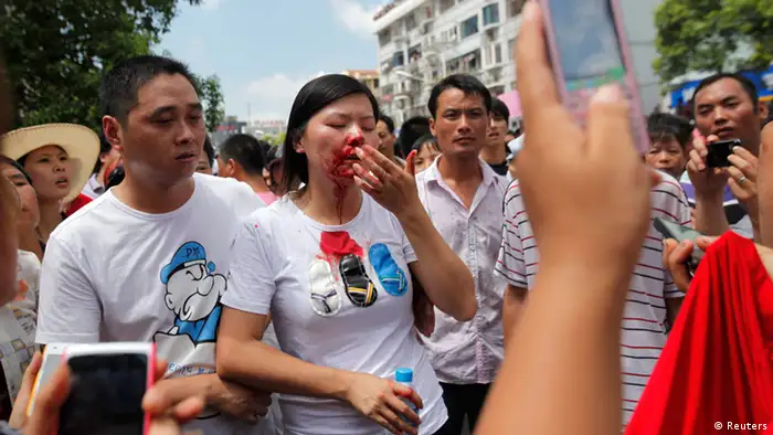A woman, with her face covered in blood, is helped by demonstrators after clashes with police during protest against an industrial waste pipeline under construction in Qidong, Jiangsu Province July 28, 2012. Angry demonstrators occupied a government office in eastern China on Saturday, destroying computers and overturning cars parked outside in a violent protest against an industrial waste pipeline they said would poison their coastal waters. The demonstration was the latest in a string of protests sparked by fears of environment degradation and highlights the social tensions the government in Beijing is having to deal with as it approaches a leadership transition this year. About 1,000 protesters marched through the coastal city of Qidong, about one hour north of Shanghai by car, shouting slogans against the plan to build a pipeline through the city that would empty waste from a nearby paper factory into the sea. REUTERS/Carlos Barria (CHINA - Tags: ENVIRONMENT CIVIL UNREST POLITICS)