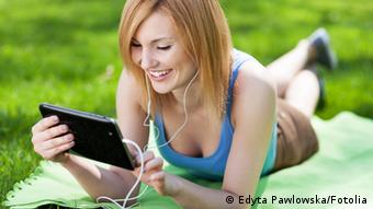 Woman lying on grass with digital tablet