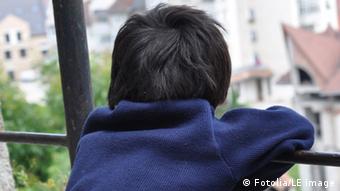 A small boy with his back turned to the camera looks out over the cityscape (Photo: Fotolia/LE image)