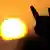 A heavy metal fan makes the devil's horn's gesture before a setting sun (Photo: Daniel Reinhardt)