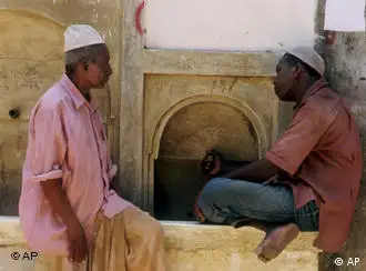 Zwei Moslems sitzen auf der Insel Lamu an einem Brunnen und unterhalten sich. Aufnahme von 2000., Two Moslems are sitting next to a fountain on Lamu Island having a chat. Picture taken 2000.