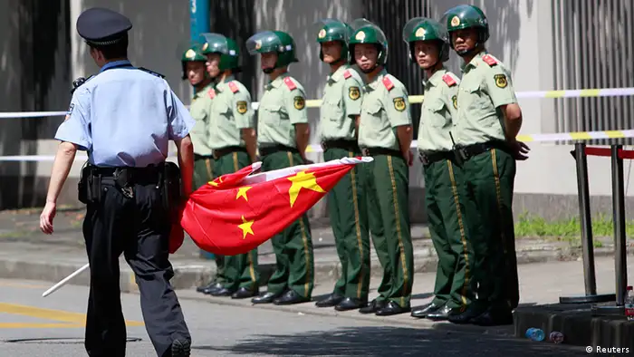 A police officer holds a Chinese national flag outside the Japanese consulate in Shanghai August 16, 2012. Protesters outside the consulate were demanding the release of detained activists after they landed on the disputed islands called Senkaku in Japan, or Diaoyu in China. China urged Japan on Wednesday to immediately and unconditionally release 14 Chinese nationals held over a protest landing on disputed islands that have long been a source of tension between the two big Asian powers. REUTER/Aly Song (CHINA - Tags: POLITICS CIVIL UNREST)