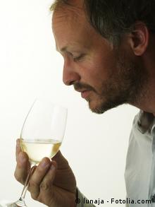 Ein Mann riecht mit geschlossenen Augen an einem mit Weißwein gefüllten Glas