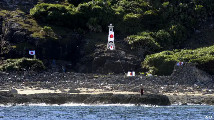 Japanese activists wave the national flag in front of a lighthouse on Uotsuri island, one of the islands of Senkaku in Japanese and Diaoyu in Chinese, in East China Sea, Sunday, Aug. 19, 2012. A group of Japanese activists swam ashore and raised flags early Sunday on one of a group of islands at the center of an escalating territorial dispute with China. (Foto:Kyodo News/AP/dapd) JAPAN OUT, MANDATORY CREDIT, NO LICENSING IN CHINA, HONG KONG, JAPAN, SOUTH KOREA AND FRANCE