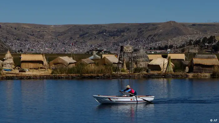 A woman rows a boat as she heads one of the Uros floating islands on the Titicaca Lake in Puno, Peru