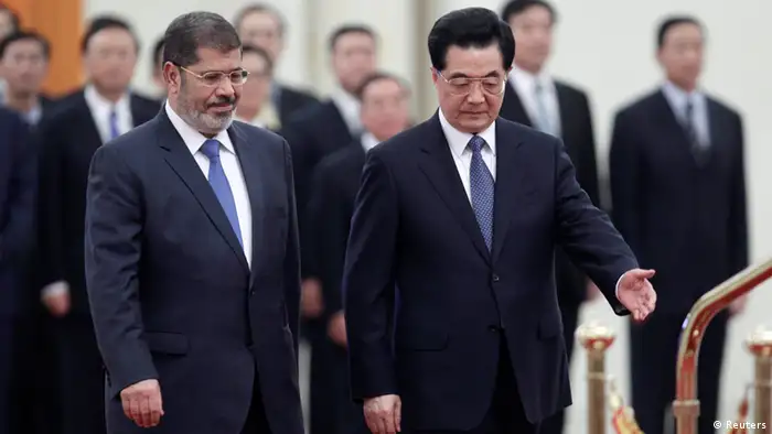 China's President Hu Jintao (R) shows the way for his Egyptian counterpart Mohamed Mursi during an official welcoming ceremony at the Great Hall of the People in Beijing August 28, 2012. REUTERS/Jason Lee (CHINA - Tags: POLITICS)
