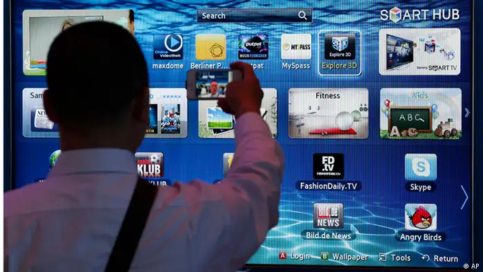 A man takes a picture with his cell phone in front of a smart TV at the IFA consumer electronics fair in Berlin, Germany, Friday, Aug. 31, 2012. (Foto:Michael Sohn/AP/dapd)