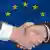 Dvije ruke koje se rukuju ispred zastave EU
