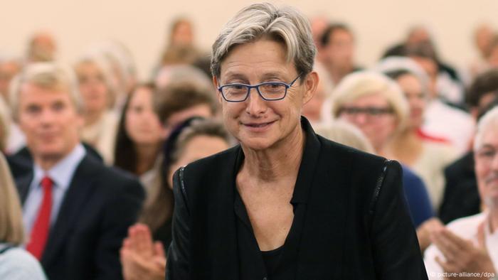 Judith Butler stands amidst a crowd of people. Judith Butler stands amidst a crowd of people.
