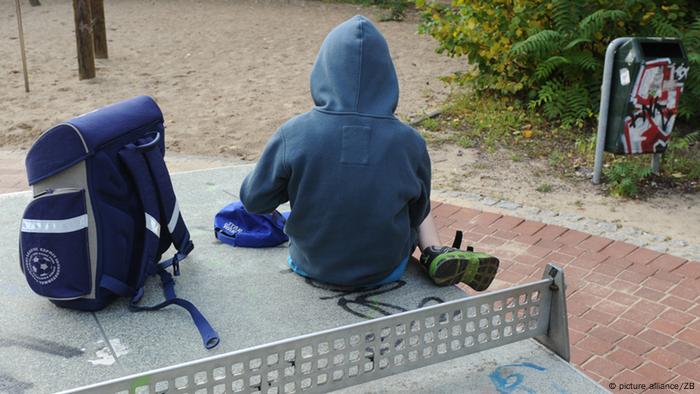 Kind mit Schulranzen auf Spielplatz
