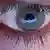 An eye with a Facebook sign reflected