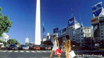 Zwei Frauen mit Einkaufstaschen überqueren vor dem Obelisken die Avenida 9 de Julio in Buenos Aires. Undatiert.
