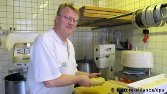 Bäcker Dirk Rauch steht in der Backstube der Bäckerei Sudbrack in Trier an einer Maschine (Foto: dpa)