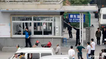 Workers clean up glass shards from the broken windows of a security room near paramilitary police vehicles parked near an entrance of a Foxconn Tech-Industry Park in Taiyuan, Shanxi province, September 24, 2012. Taiwan's Foxconn Technology Group closed its Taiyuan plant in northern China on Monday after a personal dispute spiraled into a brawl involving 2,000 workers in a dormitory late on Sunday night, injuring 40. The Taiyuan plant makes automobile electronic components, consumer electronic components and precision moldings. REUTERS/Stringer (CHINA - Tags: BUSINESS CIVIL UNREST SCIENCE TECHNOLOGY EMPLOYMENT) CHINA OUT. NO COMMERCIAL OR EDITORIAL SALES IN CHINA