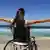 Женщина в инвалидной коляске на фоне моря