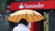 Spanish woman passing by a Santander office and holding an umbrella Spanish woman passing by a Santander office and holding an umbrella