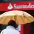 A woman under an umbrella moving towards a Santander office in Spain Photo: Fabian Stratenschulte