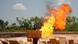 Young Nigerian carrying item next to gas flare Young Nigerian carrying item next to gas flare