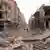 Men walk on a road amid wreckage, after three blasts ripped through Aleppo's main Saadallah al-Jabari Square, and a fourth was reported a few hundred metres away near Bab al-Jinein, on the fringes of the Old City, in this handout photograph released by Syria's national news agency SANA.