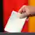 Рука, бросающая бюллетень в избирательную урну на фоне флага ФРГ