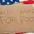 Кусок картона с надписью "Буду работать за еду", лежащий на американском флаге