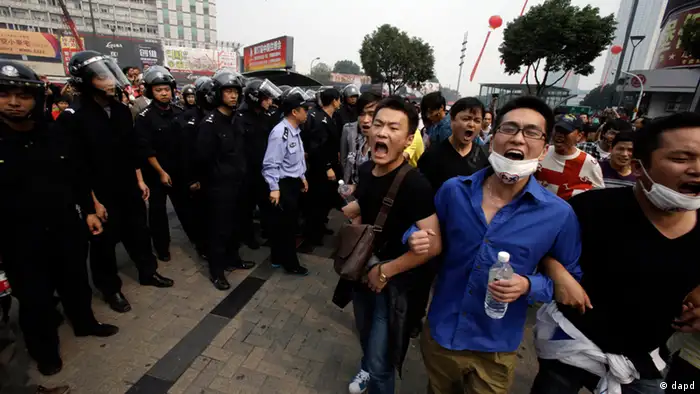 Protesters march past Chinese police men in Zhejiang province's Ningbo city, protesting the proposed expansion of a petrochemical factory Sunday, Oct. 28, 2012. Thousands of people in the eastern Chinese city clashed with police Saturday while protesting the proposed expansion of the factory that they say would spew pollution and damage public health, townspeople said. (AP Photo/Ng Han Guan)