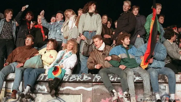 Menschen sitzen und stehen auf der Mauer und feiern (picture-alliance/ dpa/dpaweb)