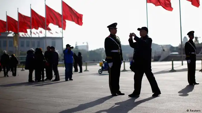 A man takes a picture next to a paramilitary police officer in front of the Great Hall of the People at Beijing's Tiananmen Square, November 7, 2012. Just days before the party's all-important congress opens, China's stability-obsessed rulers are taking no chances and have combed through a list all possible threats, avian or otherwise. Their list includes bus windows being screwed shut and handles for rear windows in taxis -- to stop subversive leaflets being scattered on the streets -- plus balloons and remote control model planes. The goal is to ensure an image of harmony as President Hu Jintao prepares to transfer power as party leader to anointed successor Vice President Xi Jinping at the congress, which starts on Thursday. REUTERS/Carlos Barria (CHINA - Tags: POLITICS ELECTIONS TPX IMAGES OF THE DAY)