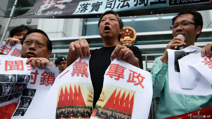 Pro-democracy activists tear a picture of the 18th Communist Party Congress held in Beijing with Chinese writing reading One party rule in China outside the Chinese central government's liaison office in Hong Kong Thursday, Nov. 8, 2012. Protesters demanded the Chinese government stop one party rule in China on the first day of a weeklong party congress in Beijing. (Foto:Kin Cheung/AP/dapd).