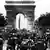 Foto histórica em preto e branco com o Arco do Triunfo ao fundo e grande movimentação de pessoas nas ruas