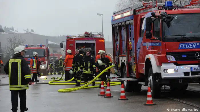 Feuerwehrmänner stehen am 26.11.2012 in Titisee-Neustadt (Baden-Württemberg) vor einer Behindertenwerkstatt. 14 Menschen sind bei dem Brand ums Leben gekommen. Foto: Patrick Seeger/dpa