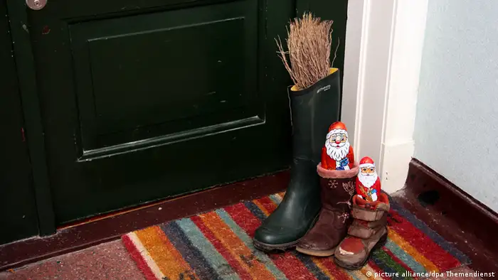 In front of an apartment door: three boots filled with sweets and a rod 