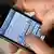 Ein Mann tippt am 23.03.2012 auf einem Smartphone eine SMS. Zum 20. Geburtstag laufen der mobilen Kurznachricht neue Online-Dienste den Rang ab. Den Mobilfunk-Anbietern entgehen dadurch Milliardenerlöse.